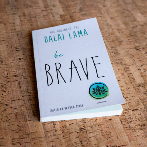 Book titled 'be BRAVE' by Dalai Lama on a wooden surface