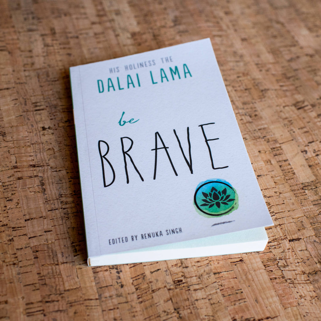 Book titled 'be BRAVE' by Dalai Lama on a wooden surface