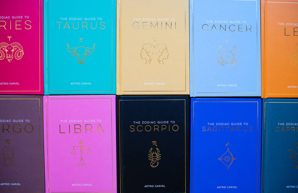Collection of colorful zodiac guide books arranged in a grid.