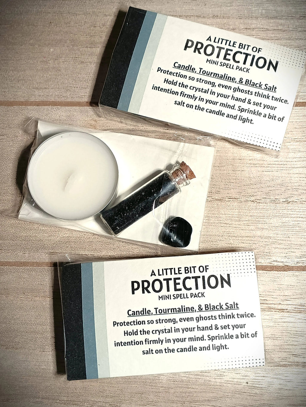 Candle, crystal, and packaging with 'A Little Bit of Protection' text on a wooden surface