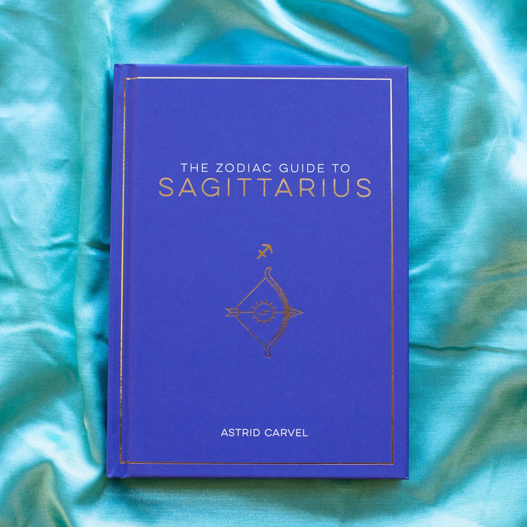 The Zodiac Guide To Sagittarius by Astrid Carvel. A purple book on a blue cloth background