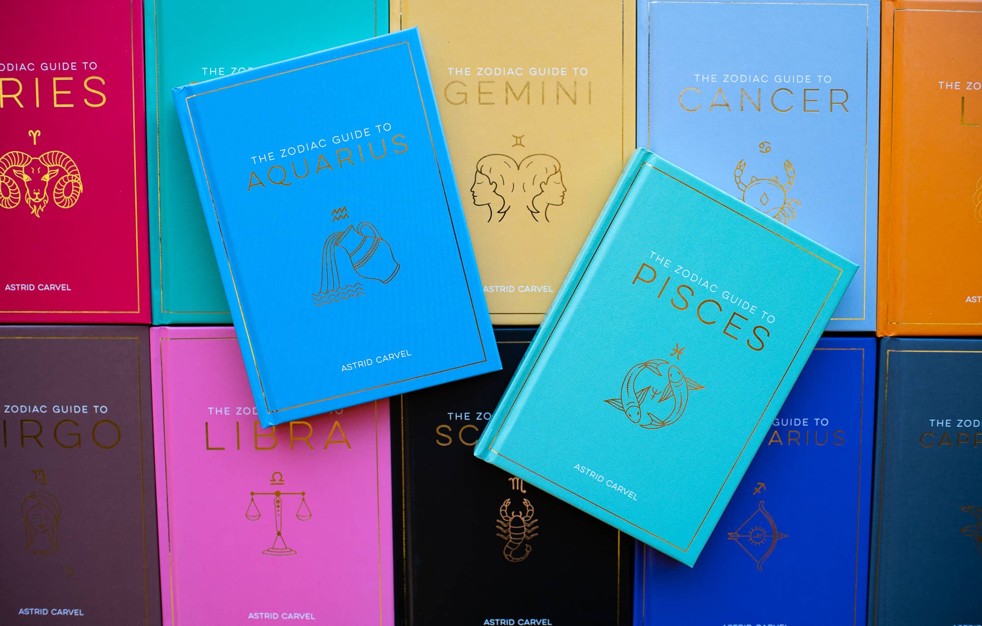 Collection of colorful books on astrology zodiac guides with visible titles and symbols.
