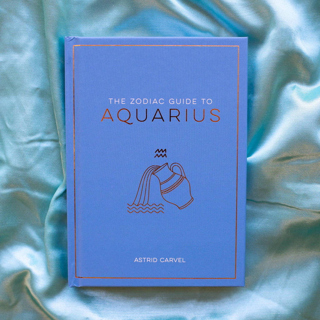 Book titled 'The Zodiac Guide to Aquarius' by Astrid Carvel on a textured blue fabric background