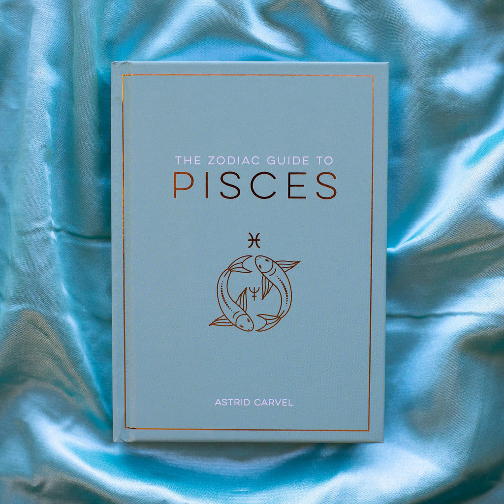 Book titled 'The Zodiac Guide to Pisces' on a blue fabric background