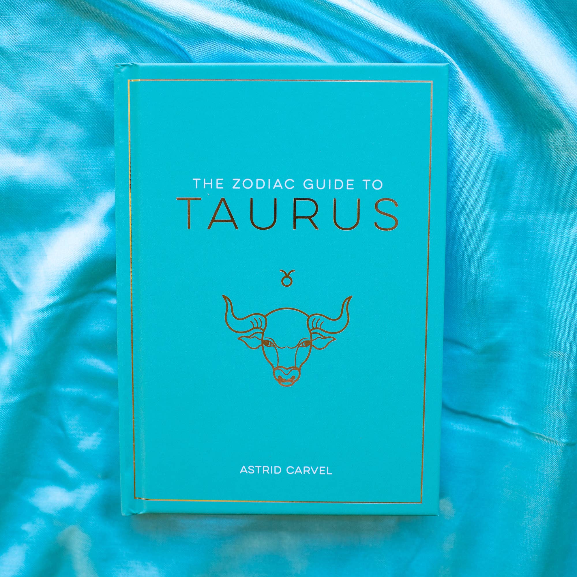 Book titled 'The Zodiac Guide to Taurus' on a blue textured background