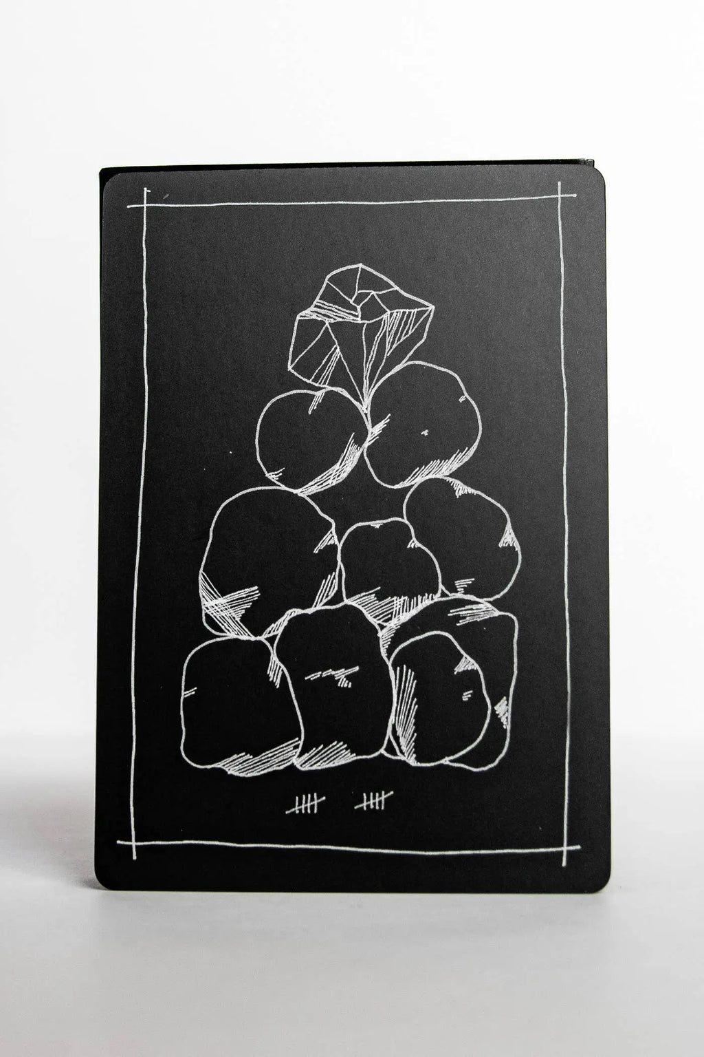 Black notebook with white line drawing of a pyramid of rocks on a white background