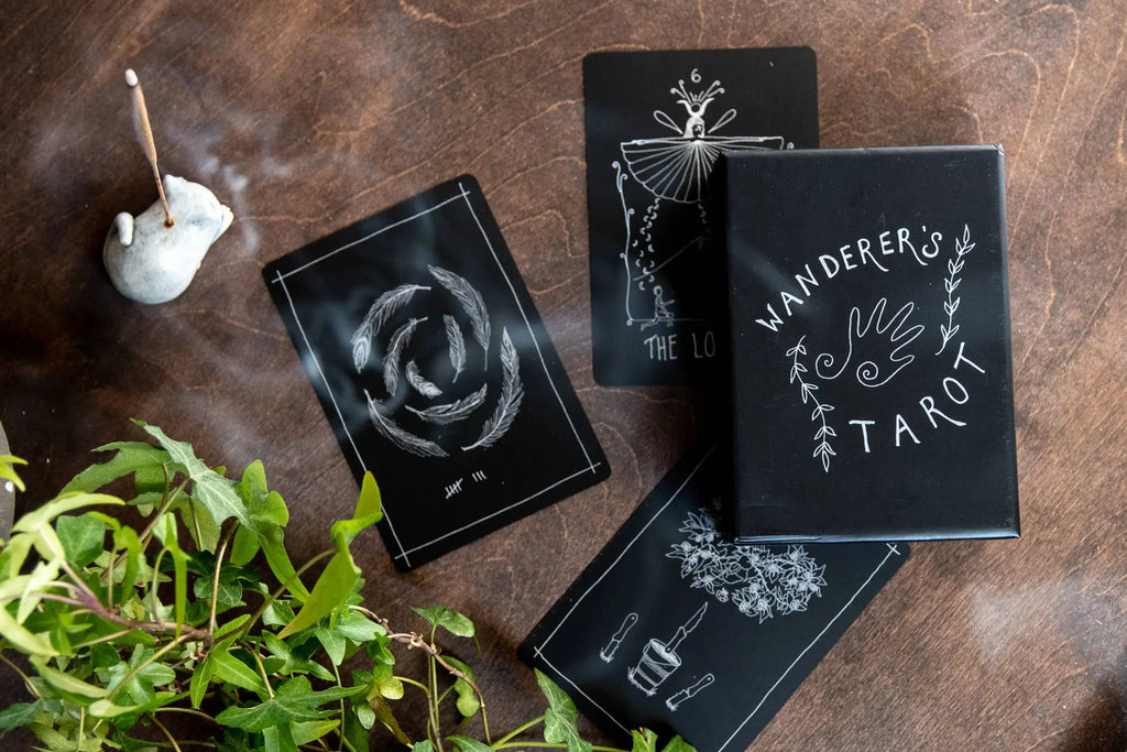 Wanderer's Tarot cards on a wooden surface with plants and a candle.