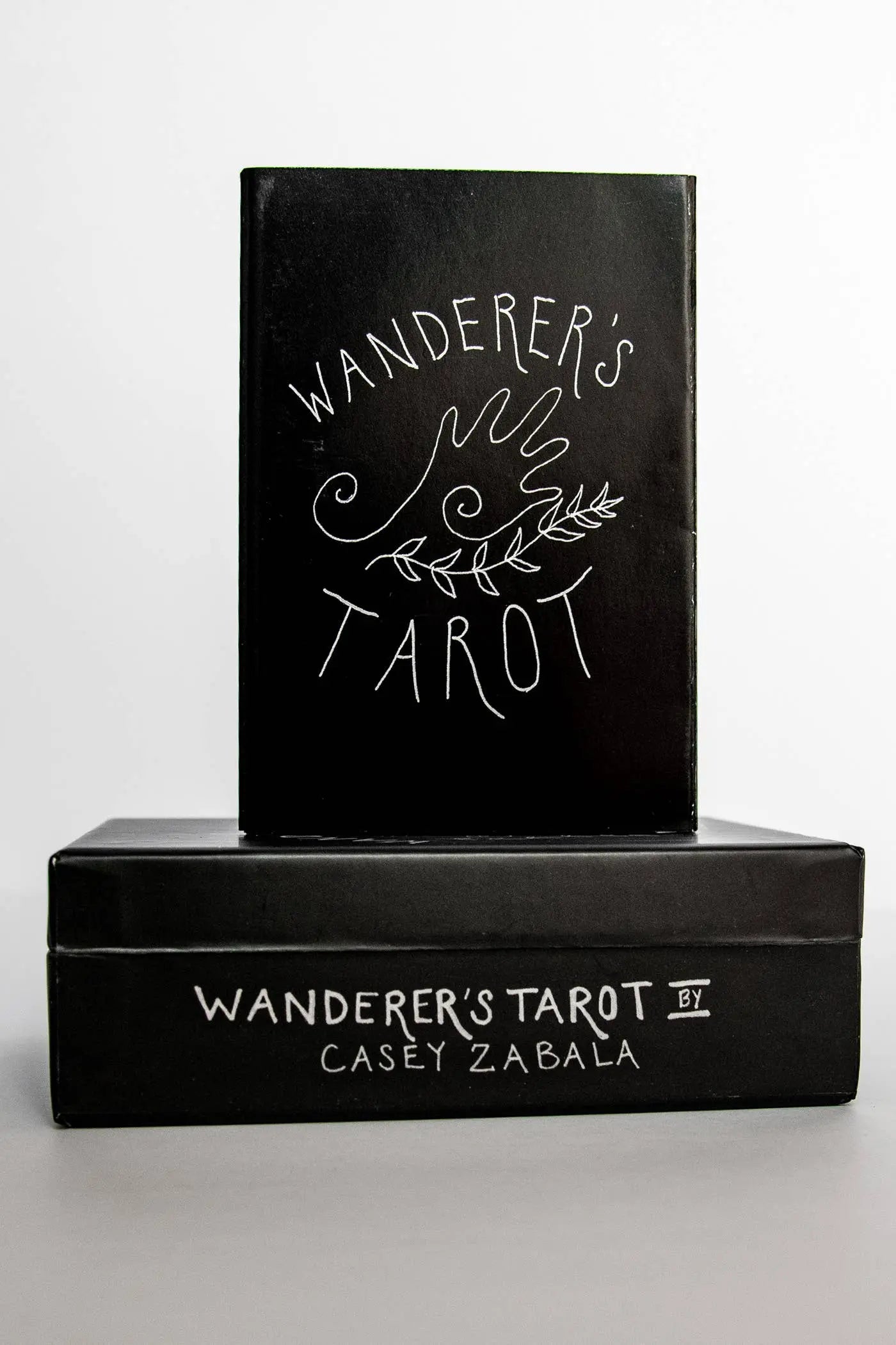 Black book titled 'Wanderer's Tarot' by Casey Zabala on a white background
