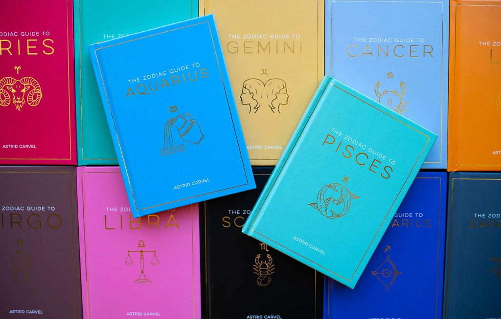 Collection of colorful books on astrology zodiac guides with visible titles and symbols.